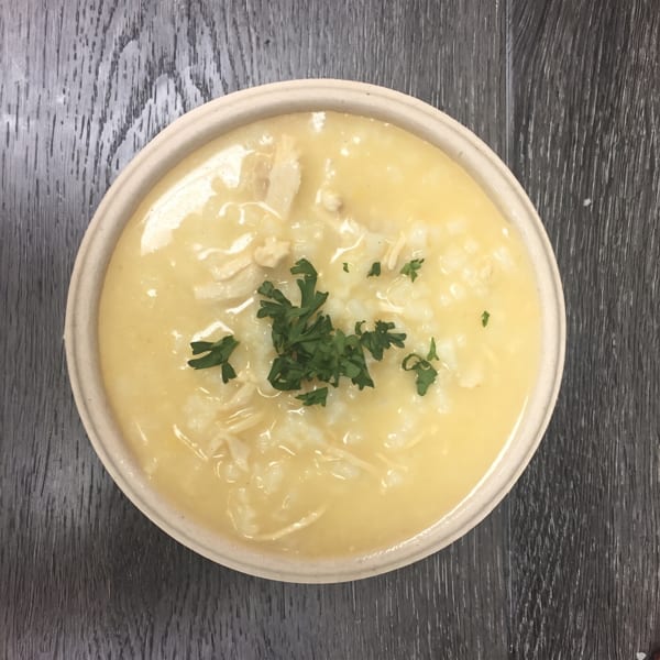 Creamy chicken and rice soup in a bowl, garnished with fresh parsley on a dark wooden surface.